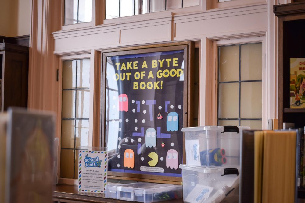 Window with construction paper art. Pac Man design with the words Take a Byte out of a good book!