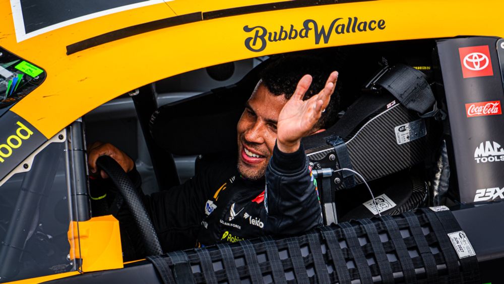 Bubba Wallace smiles and waves to fans as he drives to victory lane at Indianapolis Motor Speedway.