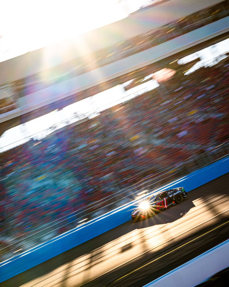 Bubba Wallace pilots his red and black No. 23 "Darth Vader" scheme into a glinting sunbeam.