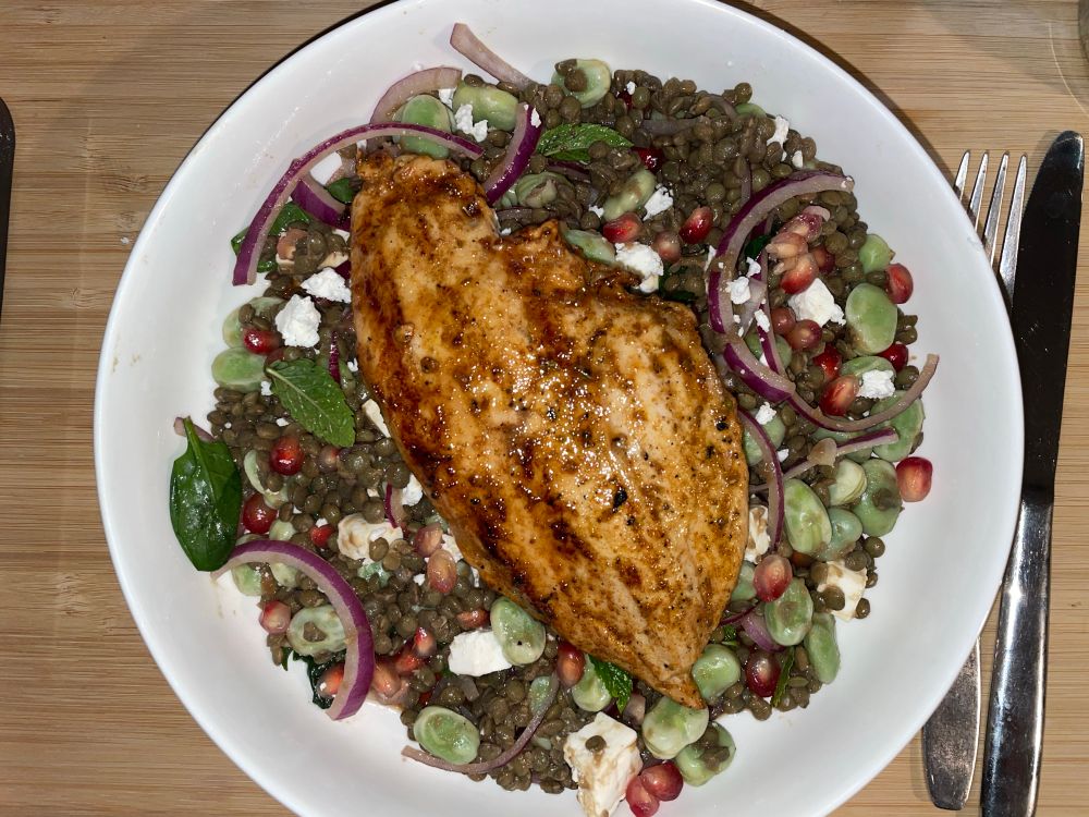 Marinaded chicken breast on a salad made from lentils, broad beans, pomegranate,  red onion, feta and mint.