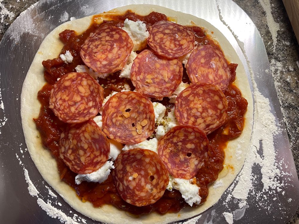 An uncooked pepperoni pizza ready for the oven.