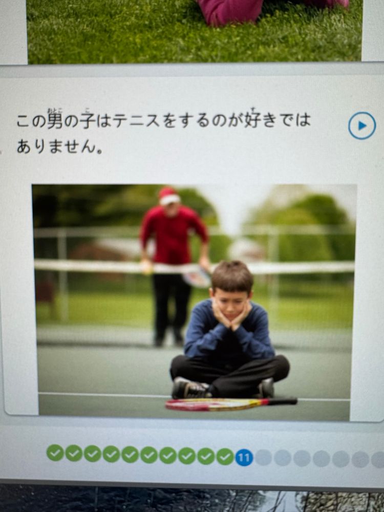 A screenshot from Rosetta Stone. Above is text in Japanese that translates to “the boy doesn’t like tennis”. Below is a picture of a kid sitting on the ground pouting with a tennis racket in front of him, while another player standing in the background looks at him.