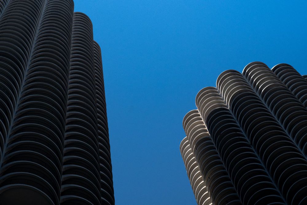 Photograph of the "corn cob" buildings at a very steep angle against a cloudless background. Sunlight dramatically only illuminates part of the right building.