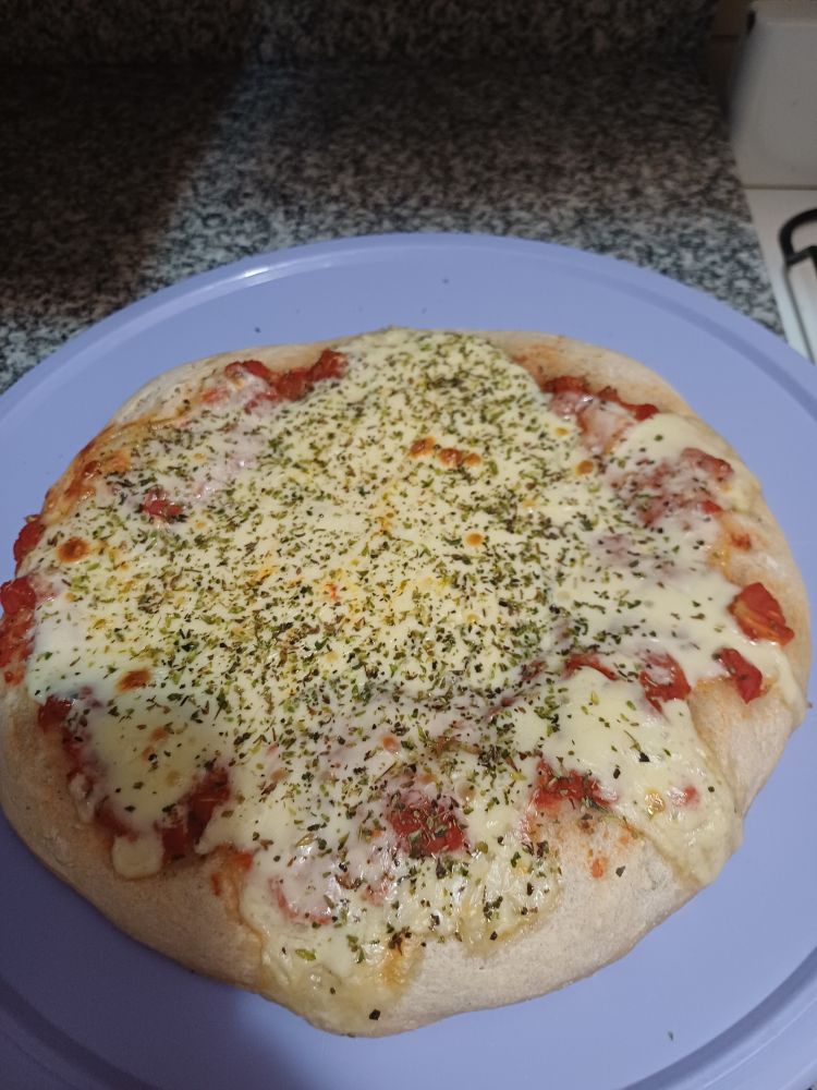 Cooked pizza on a lilac round cutting board 