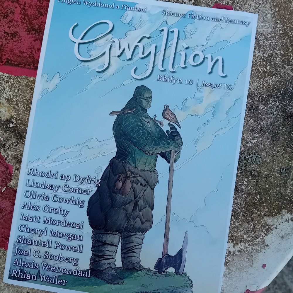 Front cover of Gwyllion Magazine, featuring Vagelio Kaliva's depiction of 'Earth Genasi Warrior'. The Warrior stands against a blue background thoughtfully holding a dove-like bird. Writers listed on the cover are Rhodri ap Dyfrig, Lindsay Comer, Olivia Cowhig, Alex Grehy, Matt Mordecai, Cheryl Morgan, Shantell Powell, Joel C. Scoberg, Alexis Veenendall and Rhian Waller.