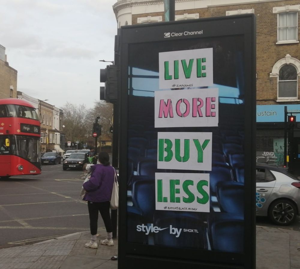 An advertising board obscured by 'Live more, Buy less' message