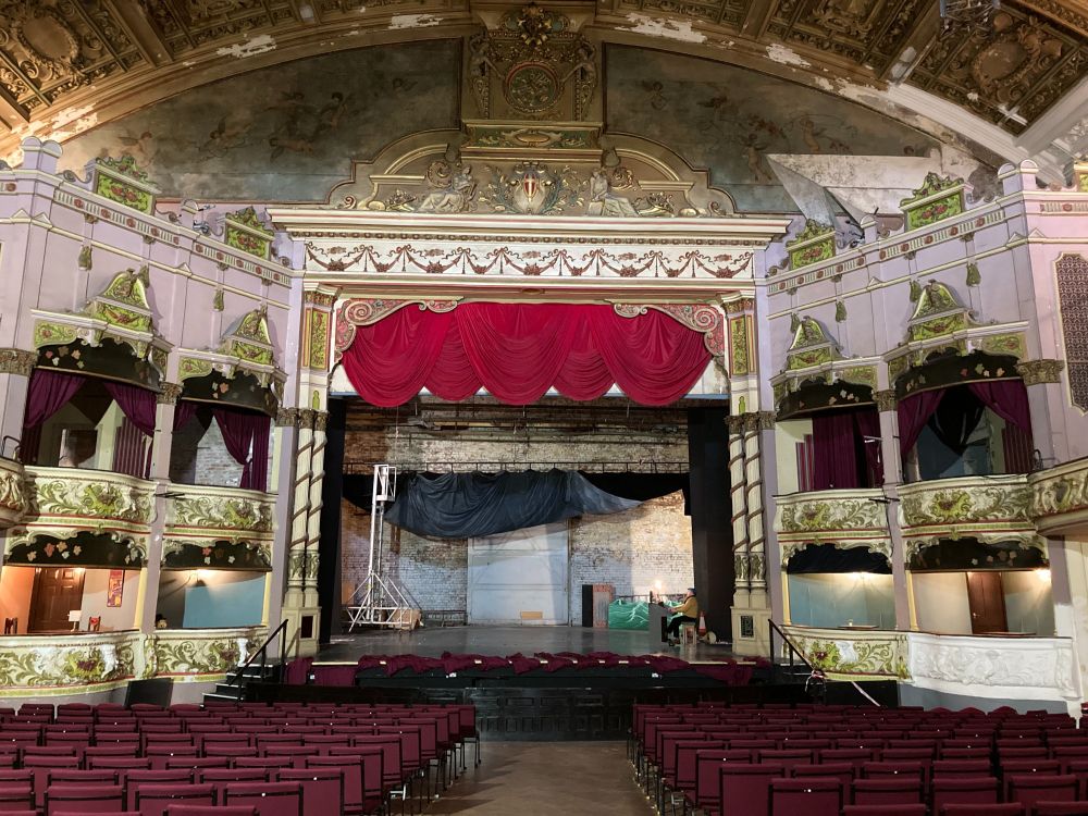 Large historic auditorium of Morecambe Winter Gardens with ornate gold plasterwork on the ceiling and boxes.