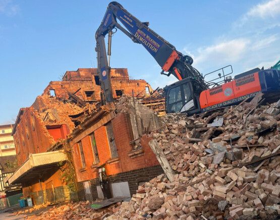 Bulldozer and a worrying pile of rubble in front of what remains of a historic theatre building