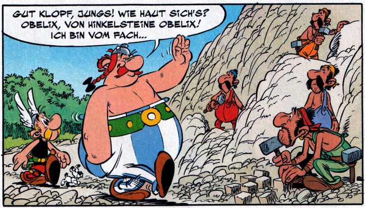 In diesem Comic-Panel stehen zwei bekannte gallische Figuren im Vordergrund. Links läuft Asterix neben Obelix ins Bild. Obelix hebt fröhlich die linke Hand und spricht Arbeiter in einem Steinbruch an. Die Szene spielt an einem hellen Felsenhang, an dem mehrere Männer arbeiten. Sie tragen einfache Arbeitsanzüge in verschiedenen Farben und stehen an unterschiedlichen Stellen des Felsens. Einige sitzen auf Steinen, andere stehen oder hämmern mit Werkzeugen in den Fels. Um sie herum liegen behauene Steinquader und Geröll. Die Arbeiter schauen zu Obelix hinüber. Oben links befindet sich eine weiße Sprechblase von Obelix: „Gut klopf, Jungs! Wie haut sich’s? Obelix, von Hinkelsteine Obelix! Ich bin vom Fach…“ Im Hintergrund wächst links etwas grünes Gebüsch, während der Rest der Szene von dem hellen Steinbruch dominiert wird.