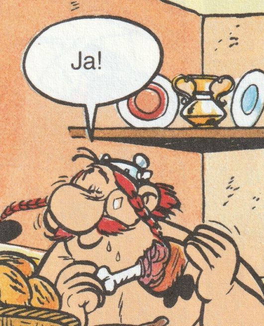 Auf dem Bild sieht man Obelix mit seinen roten Zöpfen, einem kleinen Helm, der gerade genüsslich ein großes Stück Fleischkeule isst. Aus einer Sprechblase über ihm kommt ein deutliches „Ja!“. Im Hintergrund stehen Teller und ein goldfarbener Krug auf einem Wandregal.
