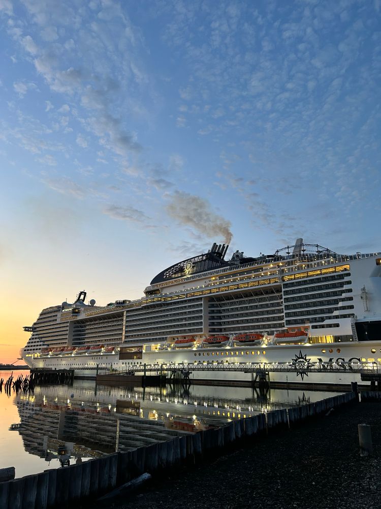 A cruise ship in Portland Maine with dirty exhaust coming out of its smoke stack. 