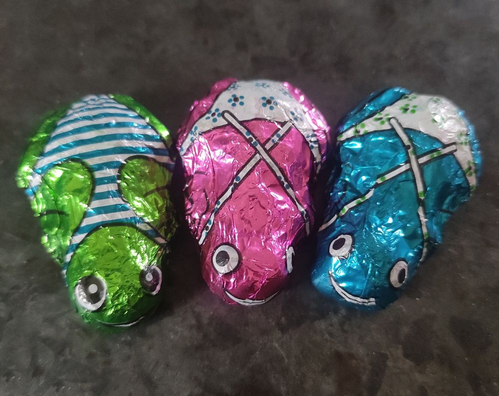 Drie snoepgoed kikkers met badpakjes. Een groene, roze en een blauwe. 