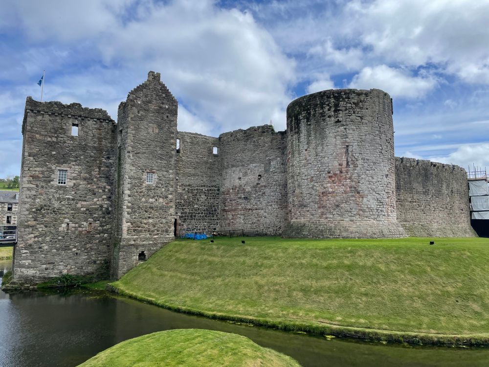 A view of the Gatehouse, the circular enclosure wall of c. 1200, and the surviving circular mural tower added in the 13th century. The castle is surrounded by a wet moat.