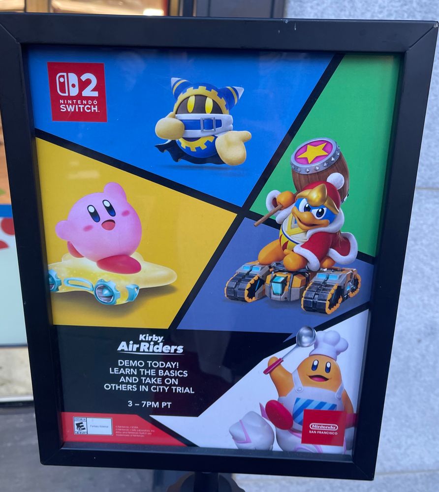 A sign outside the store mentioning the 3-7 PM City Trial demo. It had people play a handful of tutorial missions before jumping into a four player split screen City Trial match on the big screen 