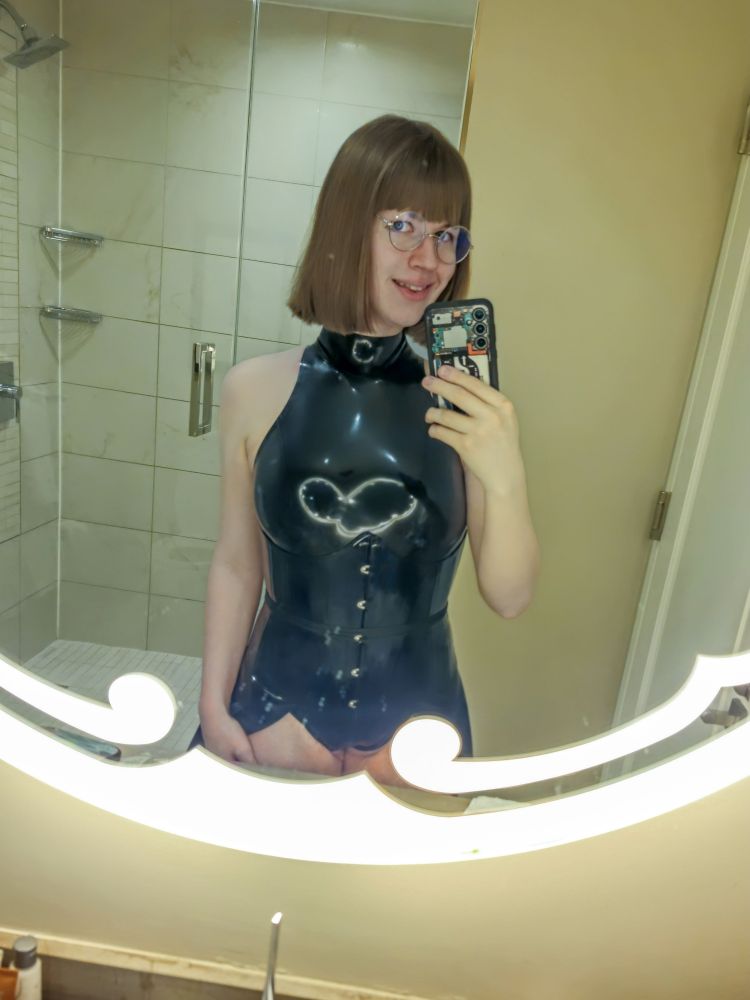 A mirror selfie of me wearing my latex swimsuit, skirt, stockings and corset