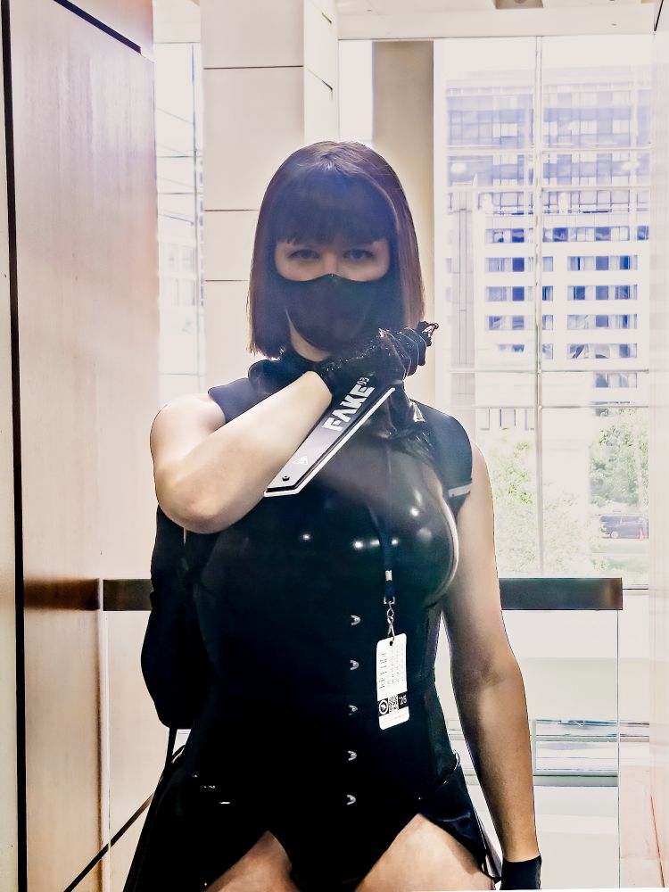 A photo of Stitch in her latex assassin cosplay and posing with a cyberpunk blade prop
