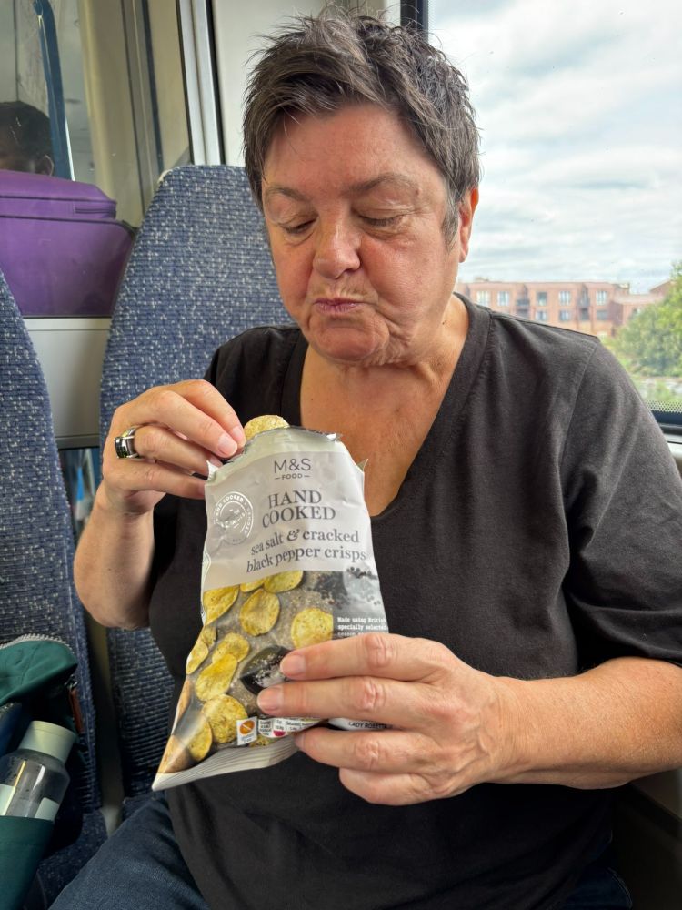 Julie Bindel yesterday eating some Marks and Spenser's hand cooked crisps on a train.