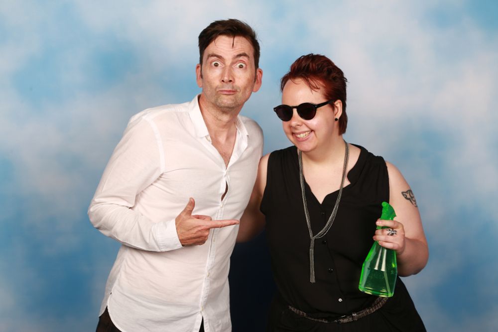 Good omens fan dressed as Crowley -armed with the iconic green plant mister -  posing with David Tennant 