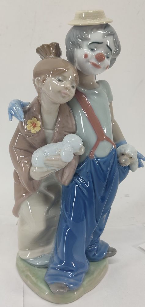 Lladro porcelain figurine of a clown with dogs in his pocket putting his hand around a woman who is wearing his oversized coat and holding a dog.