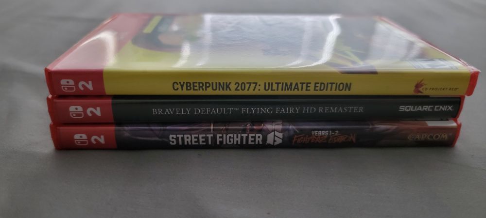 Stack of 3 Nintendo Switch 2 games from the side, showing the spines of the boxes. The games are Cyberpunk 2077 Ultimate Edition, Bravely Default Flying Fairy HD, and Street Fighter 6 Years 1+2 Edition