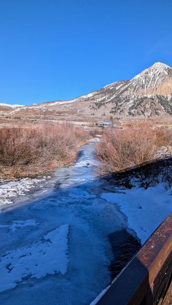 Frozen stream and mountain view from a bridge