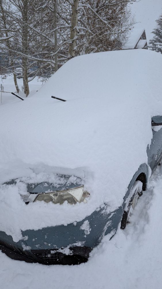 Car headlight poking thru a mountain of snow