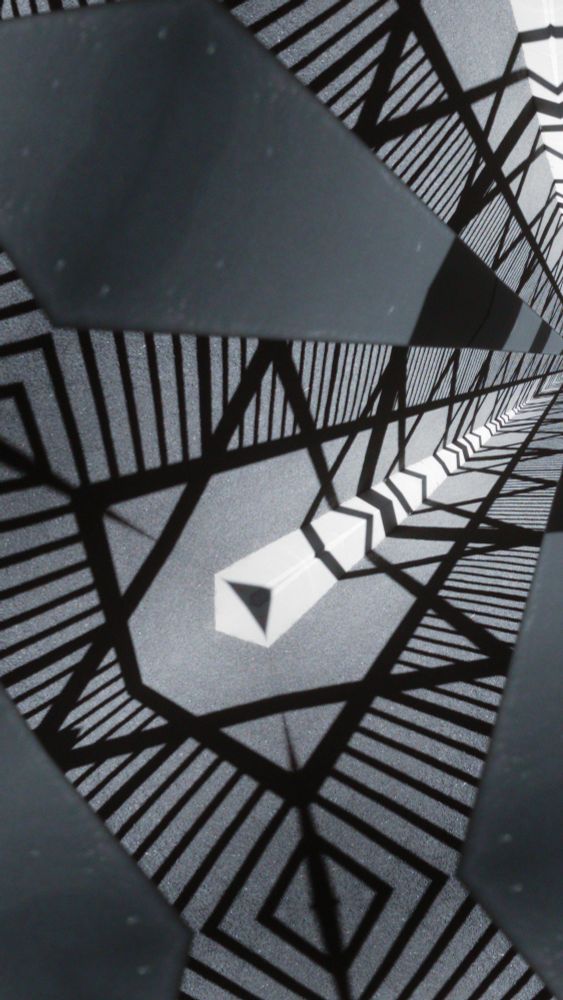 A mirrored, kaleidoscopic view of a photo of a bridge, with black, white and grey geometric patterns.