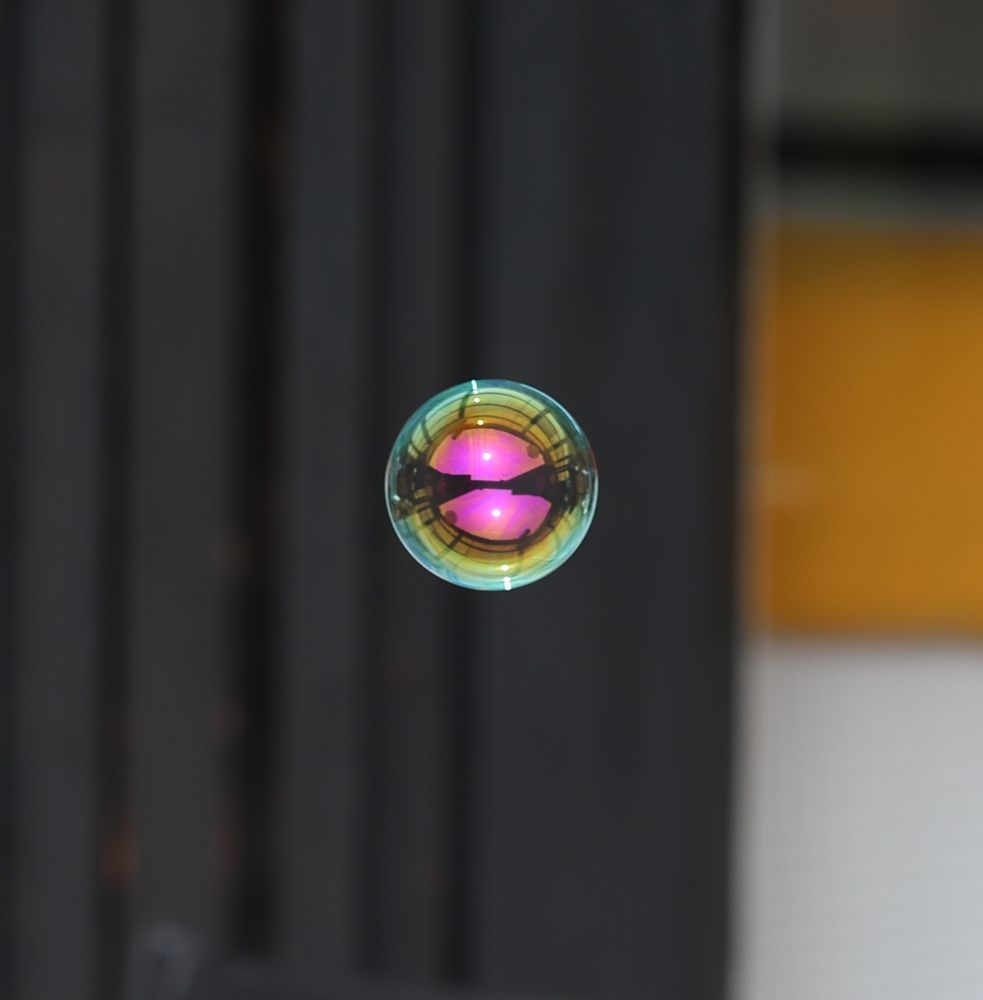 Såpbubbla med rosa center, gul ring runt, svagt blå/grön kant runt det gula.