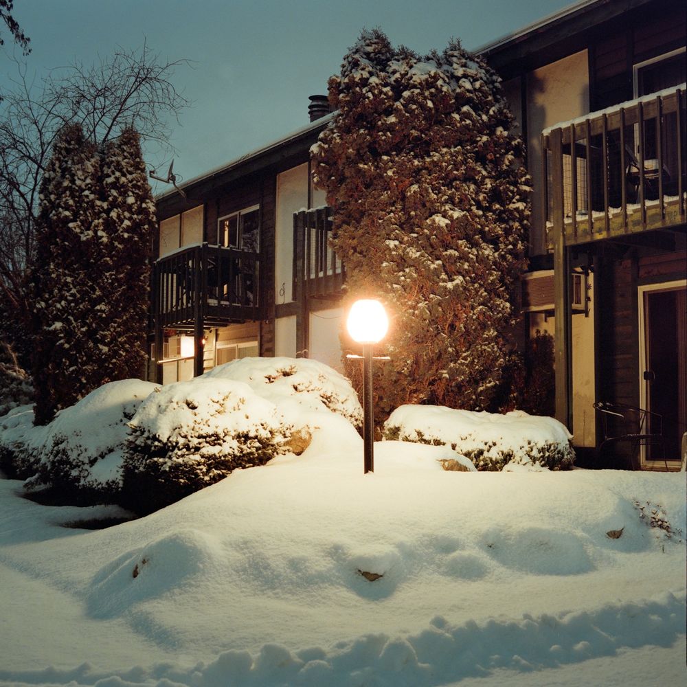 An orb style lamp post in front of an apartment complex, the ground is covered in snow