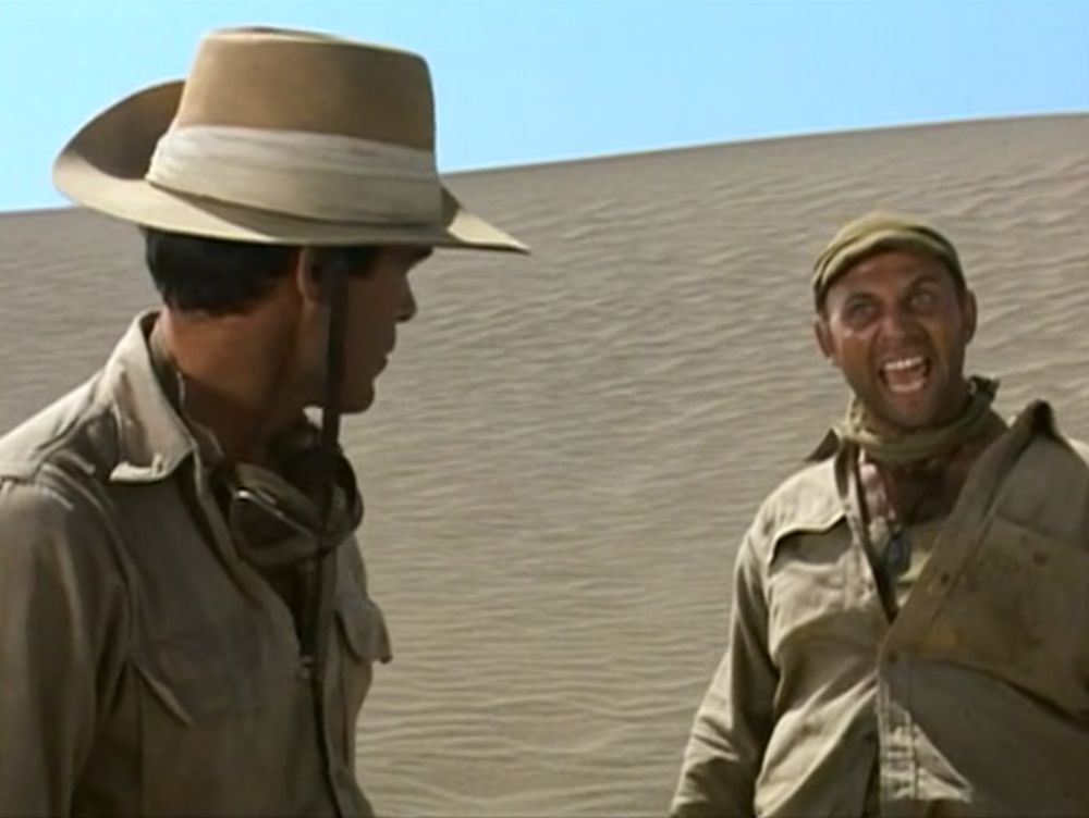Finally, in the desert dunes, screaming at the top of his lungs as Christopher George, in a consequential desert slouch hat, looks back at him seemingly unbothered.