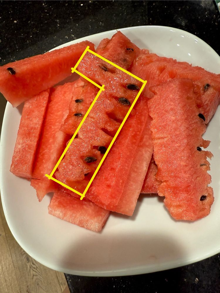A bowl of watermelon cut into sticks, with a 7-shaped piece on top. 