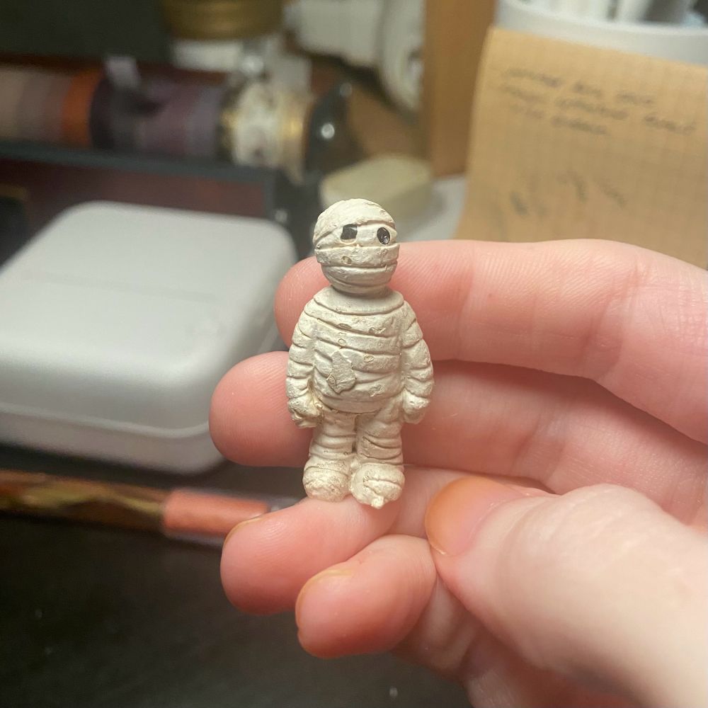 Photo of a tiny chubby mummy figurine a little over two fingers tall