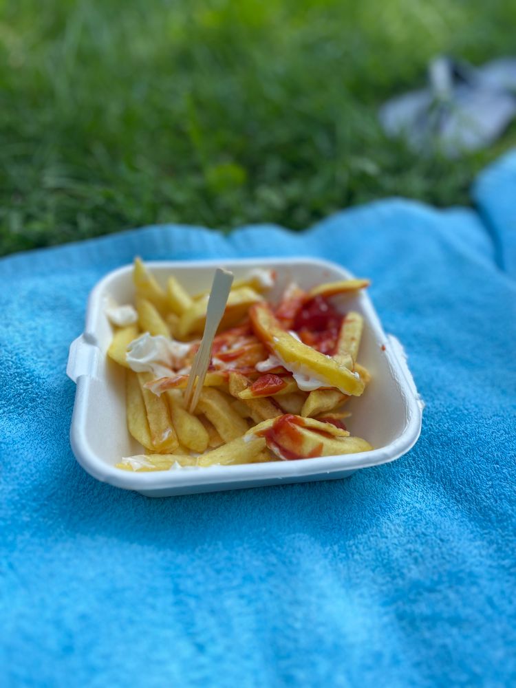 Pommes mit Ketchup und Mayo auf einem blauen Handtuch.
