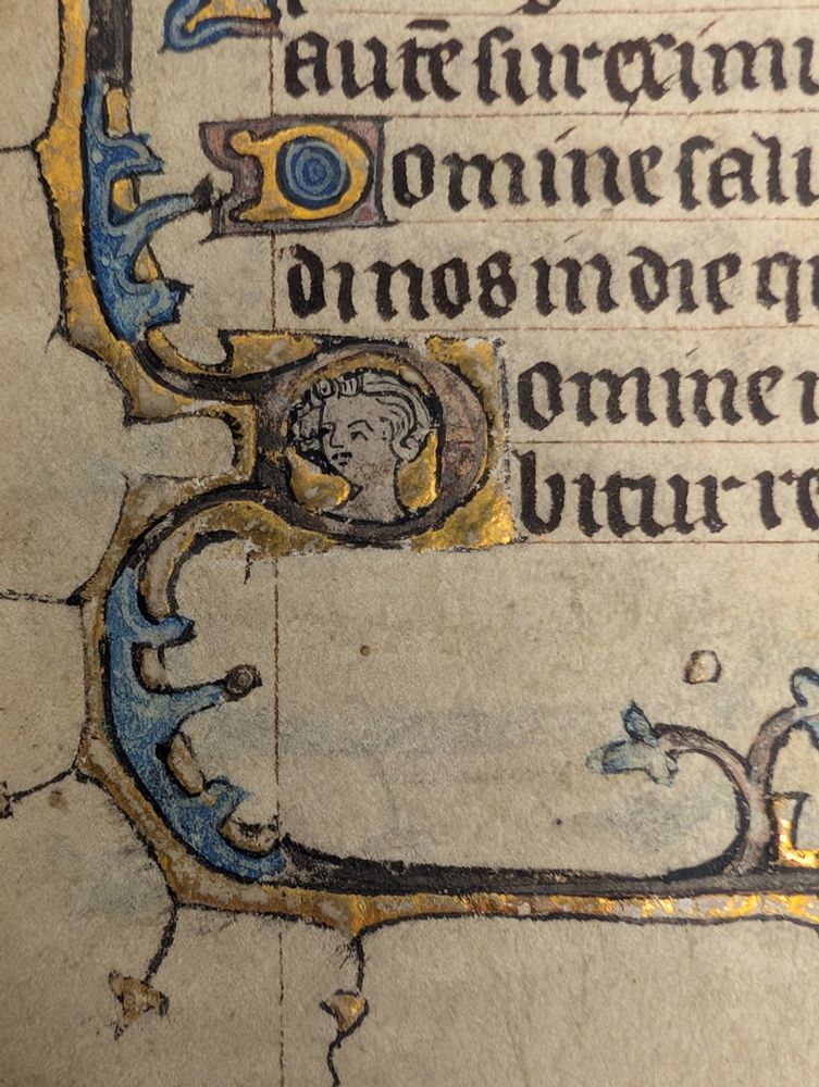 Detailed image of a small head added in an initial on a folio from a small-format illuminated Book of Hours produced in England in the 14th-century.