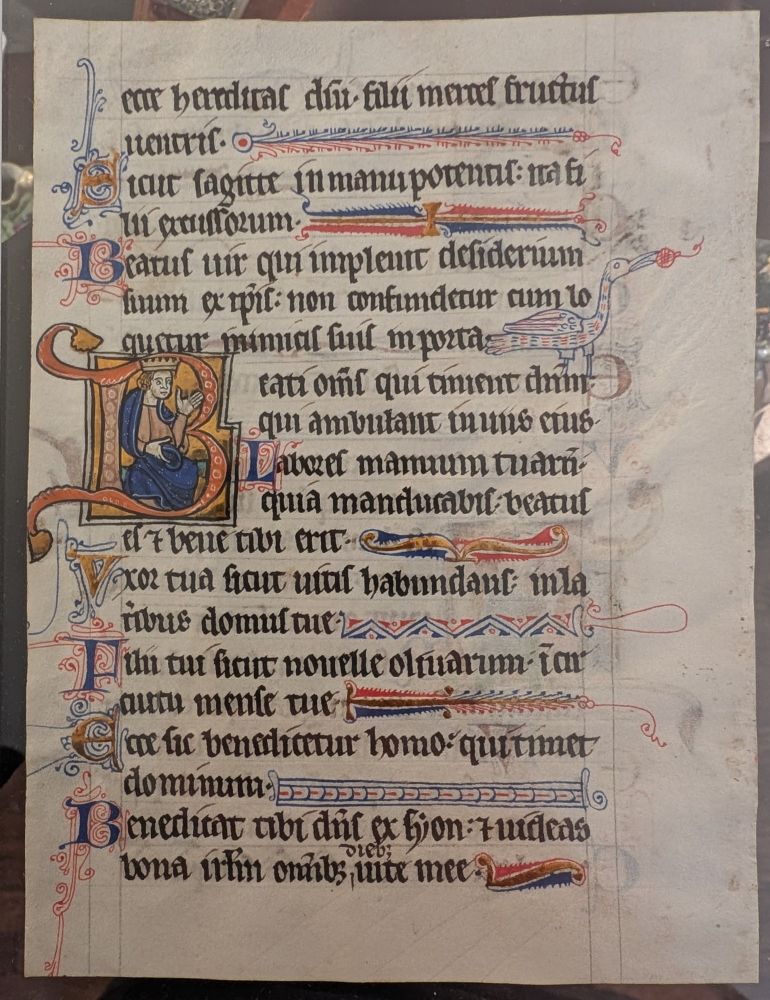 Folio from a deluxe 13th-century illuminated Psalter featuring a painted initial "B" on gold grounds inhabited by a gesturing queen or king. One of the decorated penwork line fillers depicts a blue and red goose.