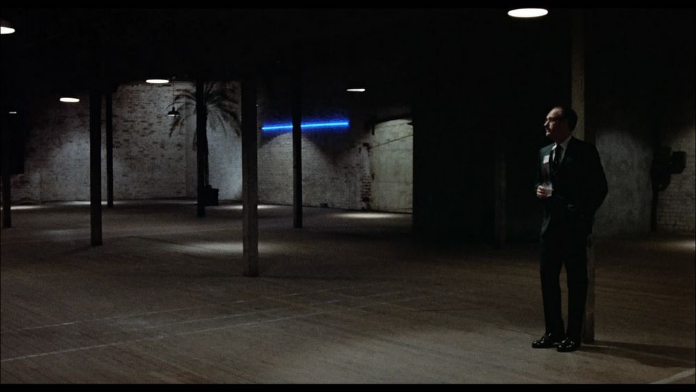 Gene Hackman in The Conversation, standing alone in a large warehouse