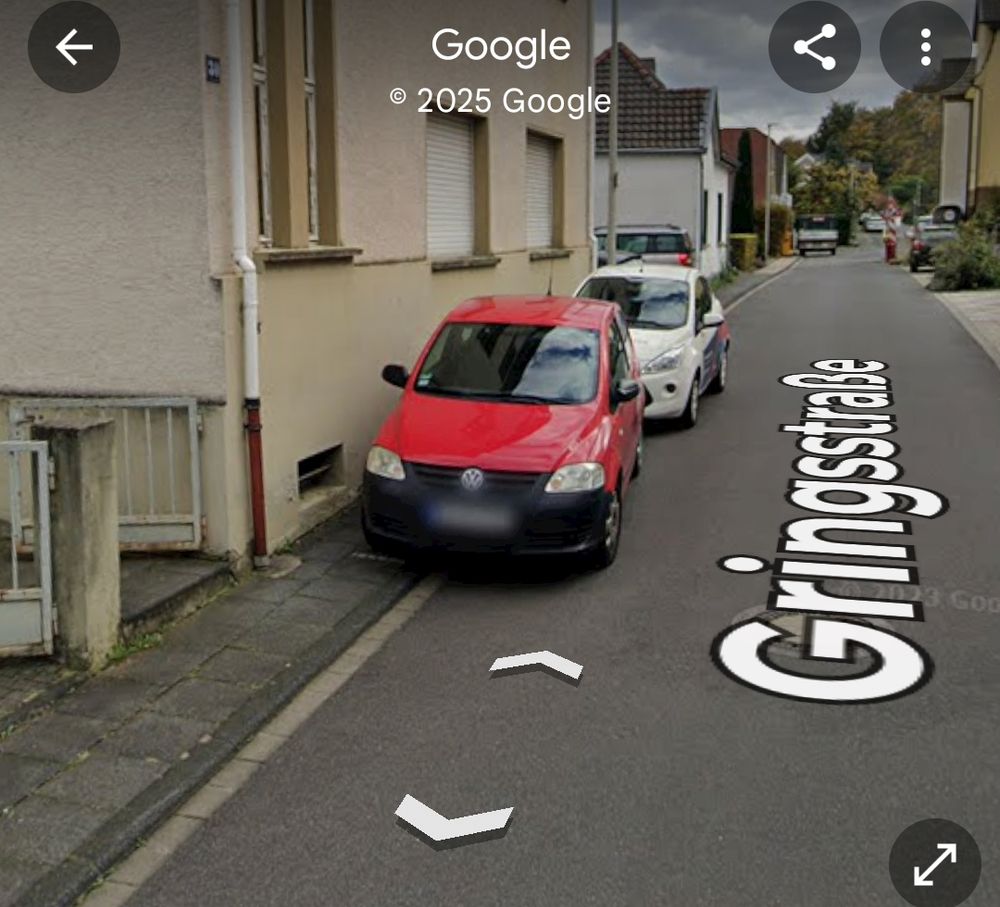 Ein rotes und ein weißes Auto, geparkt in einer engen Wohnstraße auf einem sehr schmalen Gehweg, so dass ein durchkommen auf dem Gehweg für Fußgänger nicht mehr möglich ist. 