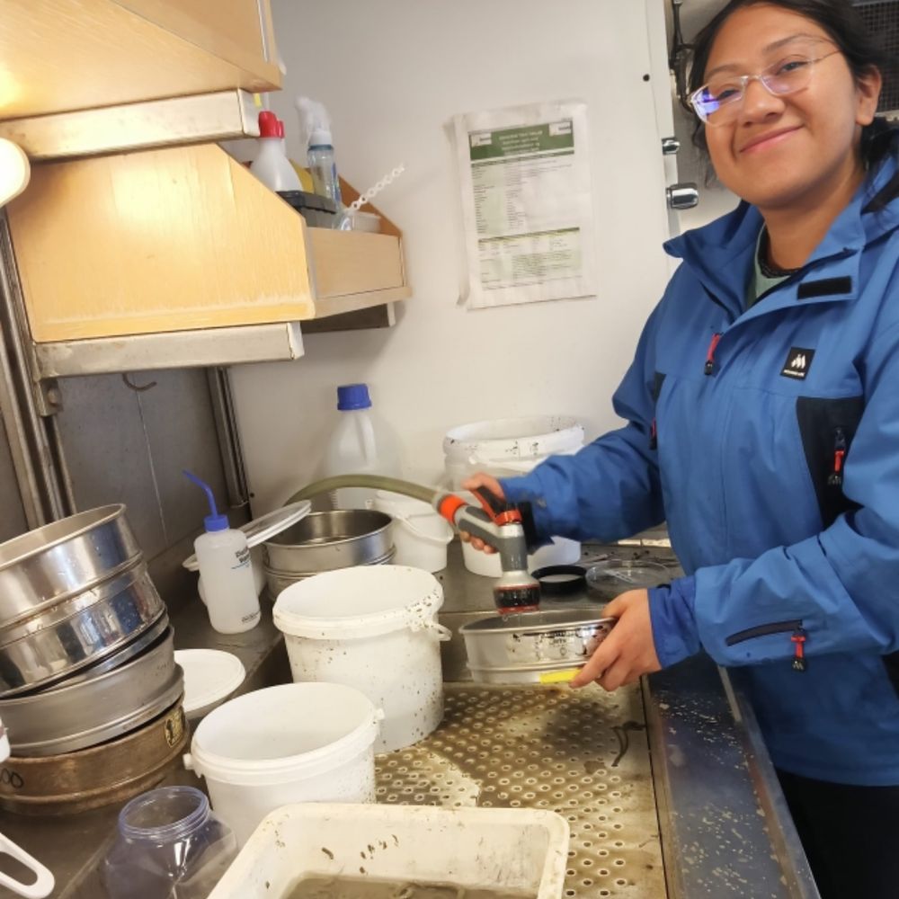 "For this, I am using phylogenetics and Restriction-site associated DNA (RAD) sequencing. I will also study the microbiome associated with these gastropods to get insights into their ability to inhabit different CBEs."

(Image: Brenda smiling while rinsing a sieve in a lab.)