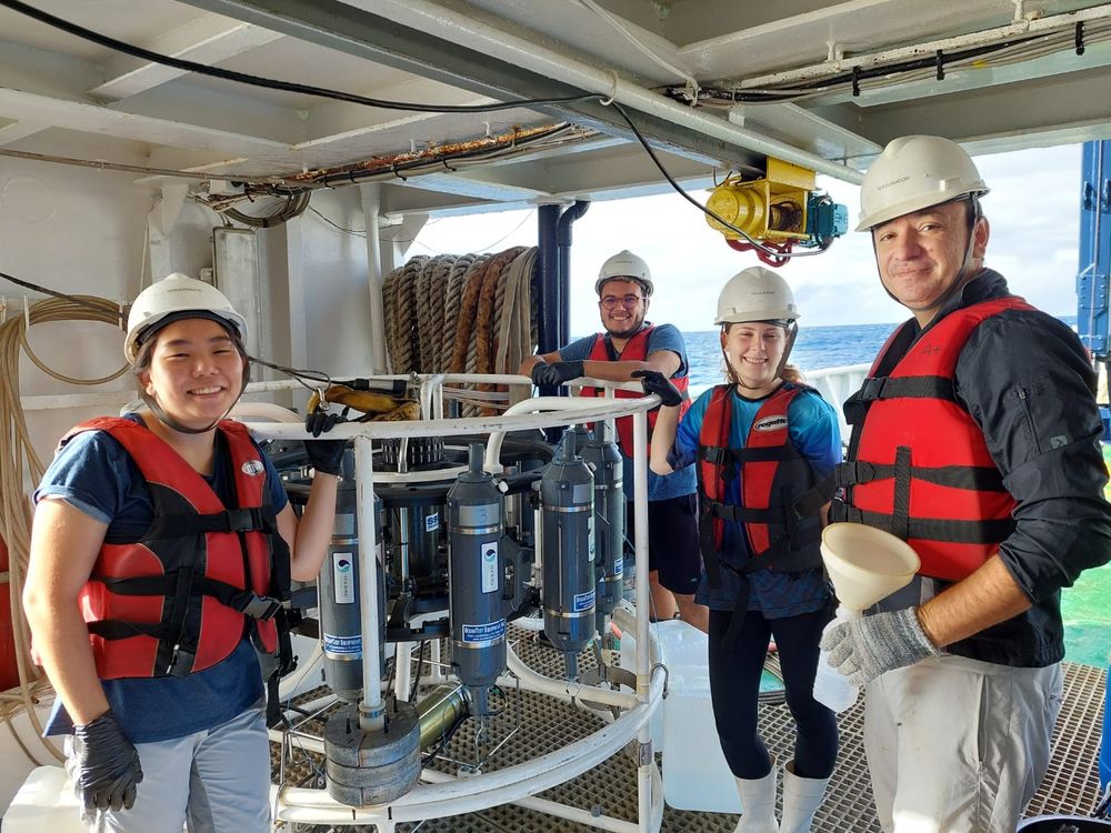 "It was my first time on a research vessel and a huge opportunity that started guiding my path toward deep-sea research. During the expeditions, I observed many different and unique species of fish and invertebrates, such as deep-sea corals, ophiuroids, and anemones, including new and rare ones."

(Image: Flávia smiling and holding the side of a CTD instrument. She’s accompanied by three other smiling scientists, one of them being another 17DSBS conference support awardee (Heloísa de Cia Caixeta). Everyone is on the deck of a boat and wearing orange safety vests and hard hats.)
