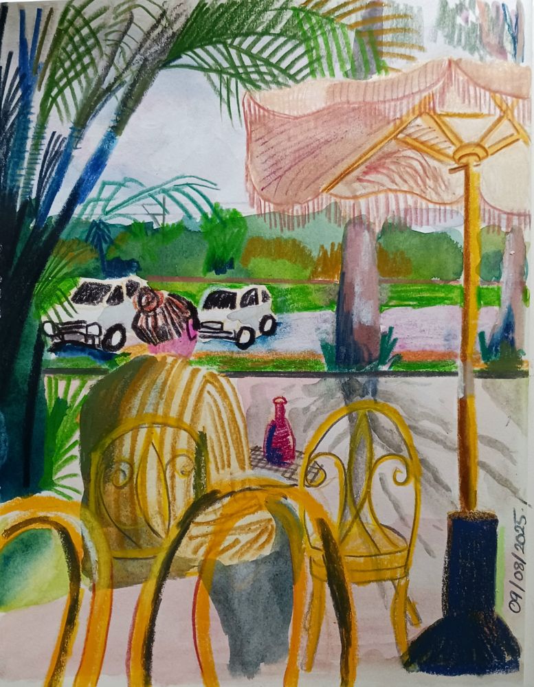 Sketchbook page shows a drawing of a woman from behind sitting at a cafe. Yellow chairs, pink umbrella, and palm trees surround her. Across the road are big gum trees, a car park, and distant hills