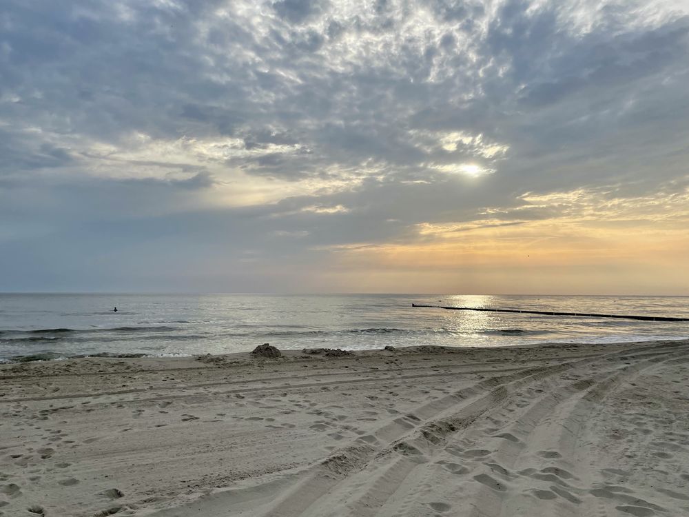 Blick auf die Ostsee Richtung aufgehender Sonne, die hinter leichten Wolken ist. 