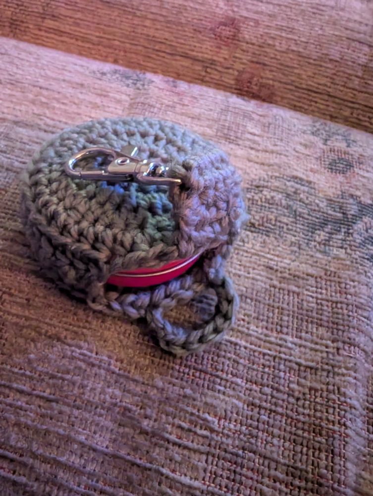Crochet holder showing a tin of vaseline secured inside.