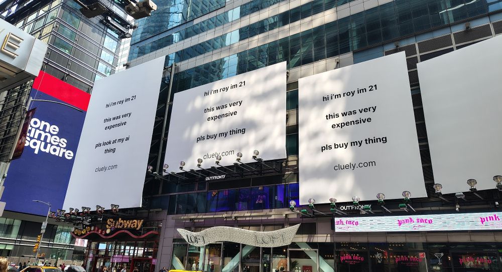three large billboards in times square. they are white with black text that says some variation of "hi my name is roy im 21 this was very expensive pls buy my thing" it is ai garbage.