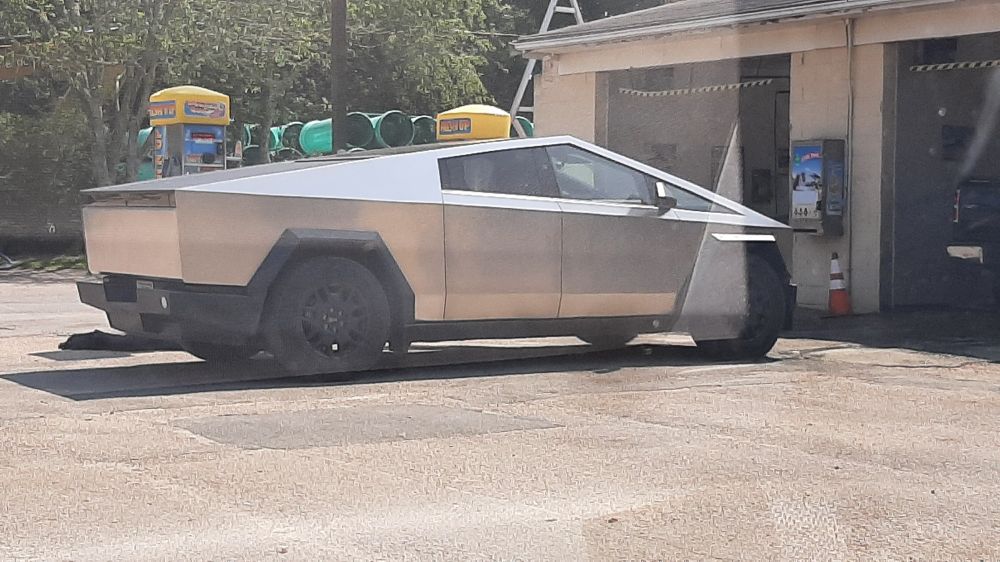 Photo of stupid tesla cybertruck outside a car wash.