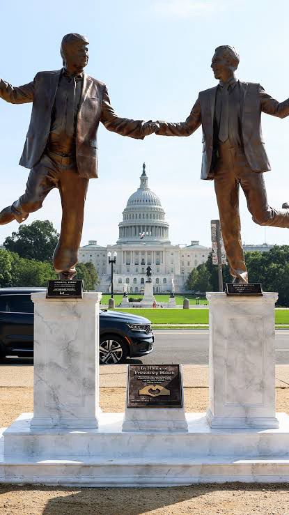 Statue of Trump and Epstein holding hands in view of the Capitol in the background.