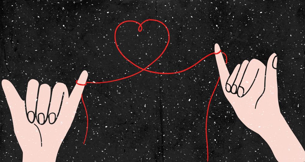 Two hands on either side with their thumb and pinkies up. A red string connects their pinkies, forming a heart between them. On a black background with white snow. 
