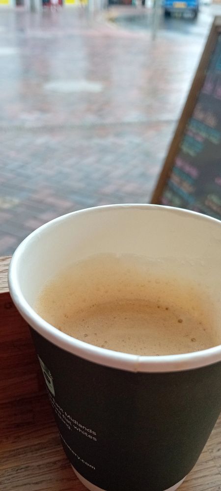 A view of a rain drenched street from an English cafe window, small coffee in the foreground.