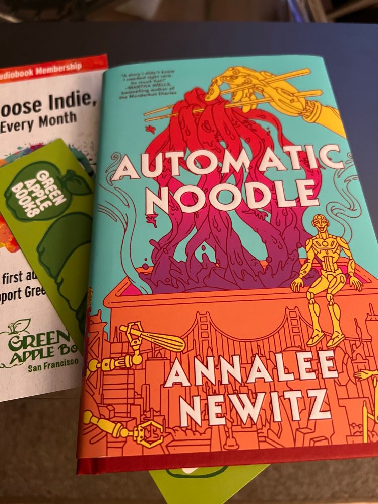 Picture of the hardcover of Automatic Noodle, by Annalee Newitz. And some marketing from Green Apple Books in SF. The cover shows a robot hand picking up noodles with chopsticks above a stylized view of San Francisco. 