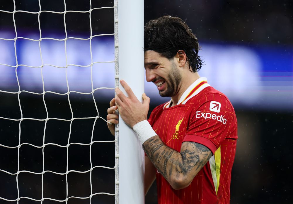 Liverpool midfielder Dominik Szoboszlai holds and rests his head against a goalpost at the Etihad Stadium.