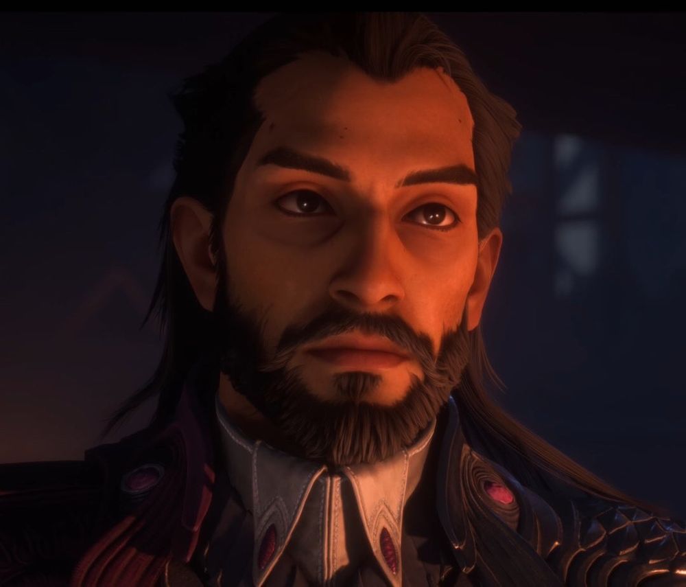 Lucanis Dellamorte from Dragon Age: The Veilguard. He has shoulder length black hair and brown eyes and a close cropped beard. He is looking towards the camera, and almost looks tearful.